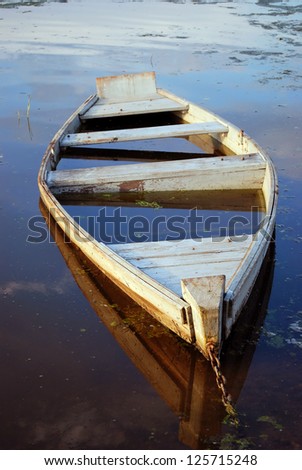 The flooded wooden boat on river bank