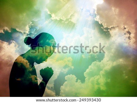 Silhouette of young woman praying to God