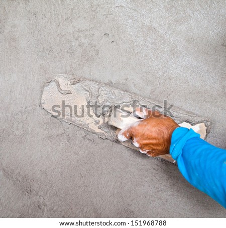 Close-up of hand using trowel to finish wet concrete wall