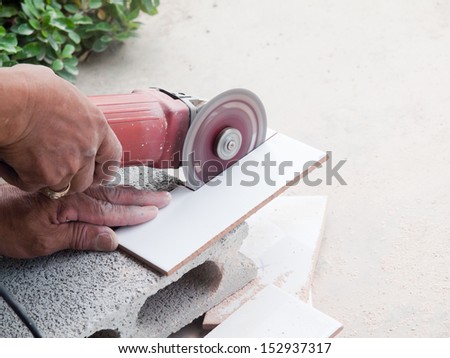 A construction worker using an angle grinder cutting tile
