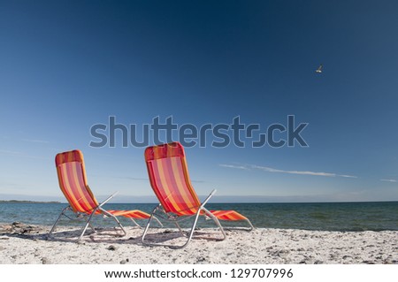 Lounging beach chairs on the Lake Ontario shoreline with large copy space area in the deep blue sky