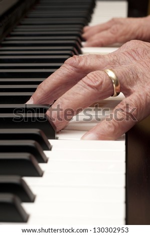 Selective focus on the foreground hand of an older man playing the piano