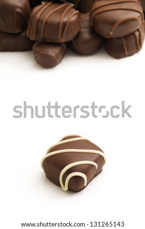 Vertical image with selective focus on the single chocolate in the foreground with multiple chocolates in the background