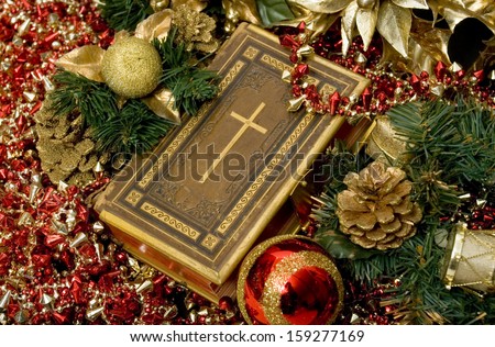 Selective focus on Bible surrounded by Christmas ornaments.