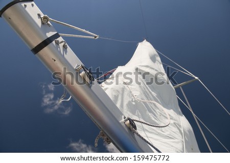 Closeup of a portion of the sailboat beam with sail in the background on intense blue sky