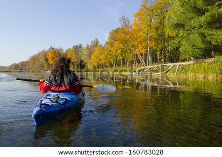 Woman in the her kayak on a tranquil lake in early October
