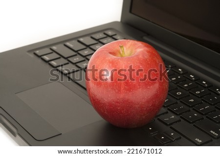 Red apple resting on a laptop keyboard, concept; health, healthy computer
