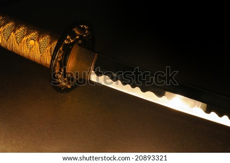 a close up shot of a samurai sword lit by candel light