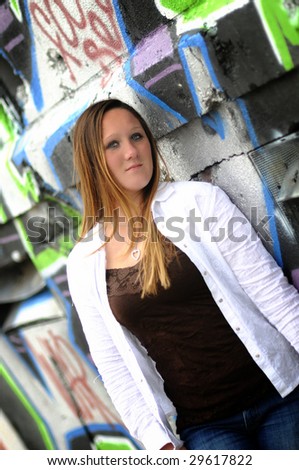 a young woman standing next to a graffiti wall