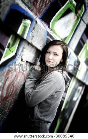 a young woman posing in front of a graffiti wall