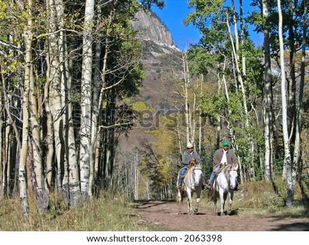 Men riding horses on a trail in the mountains of Colorado