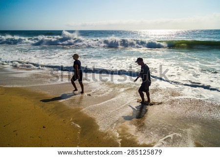 HALF MOON BAY, CALIFORNIA - 4 SEPTEMBER 2014: An old couple walking in the waves on beach of Half Moon Bay, California, USA