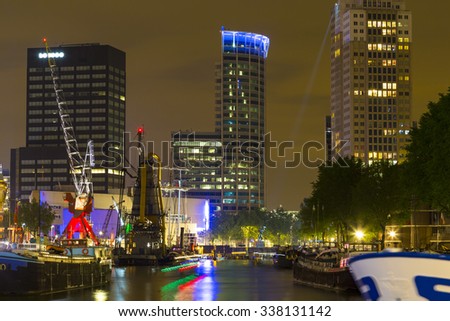 Illuminated old cranes and modern office buildings at night in historical harbor of Rotterdam, Netherlands