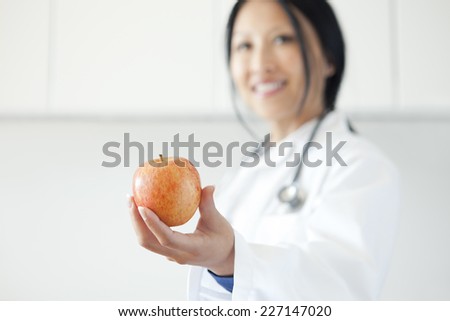 Woman doctor proposing an apple for a healthy life with selective focus on the apple.