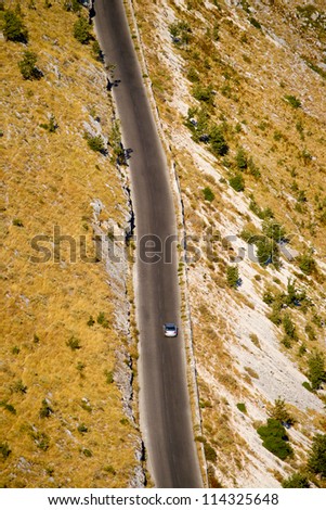 Aerial view of a desert highway with a car driving on it