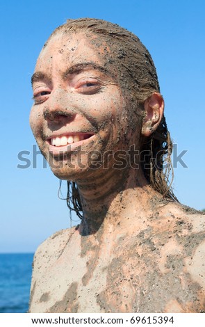 Young beautiful smiling woman getting a body mud therapy
