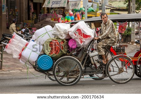 PHNOM PENH, CAMBODIA - MARCH 21: Plastic ware vendor driving his bicycle in Phnom Penh, Cambodia on March 21, 2014