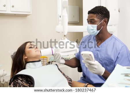 african american dentist or dental tech taking an X-ray during an exam