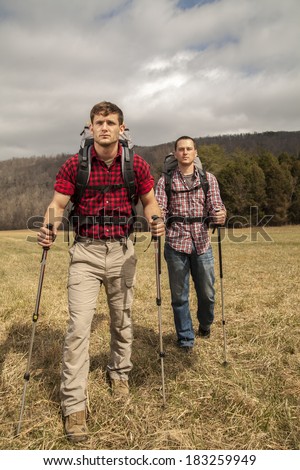 two hikers with backpacks and walking sticks walking to the campsite