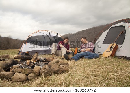 hikers eating dinner by the fire at the campsite