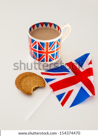 A cup of milky english tea in a british union jack mug with  digestive biscuits and a british flag