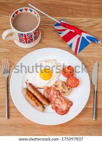 English breakfast on a wooden table top with  cup of tea  and british flag in portrait