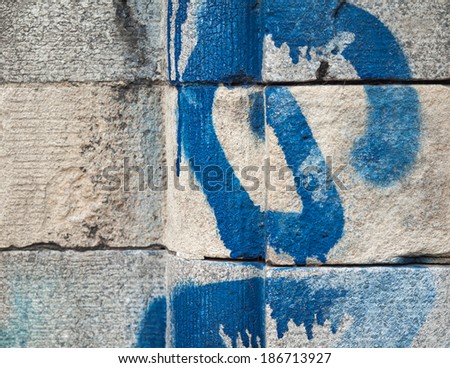 Detail of rough textured grey architectural stonework with blue spray paint graffiti