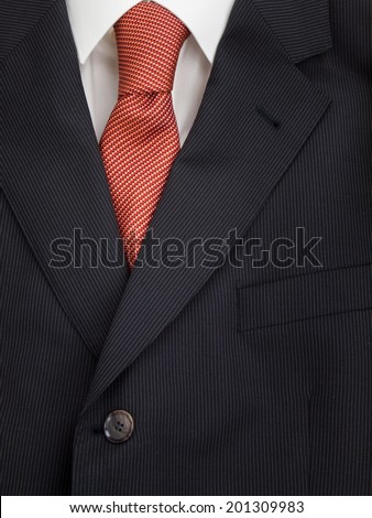 detail of mens pinstripe suit jacket lapel with  shirt and orange speckled tie