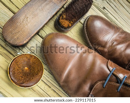 old brown leather shoes with shoe polish and antique brushes against  aged cracked  wooden boards