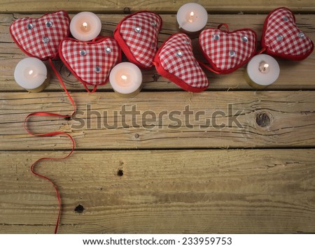 red check hearts  with candles and  red ribbon on rustic wooden background