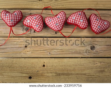 line of of five red check hearts  with red ribbon on rustic wooden background