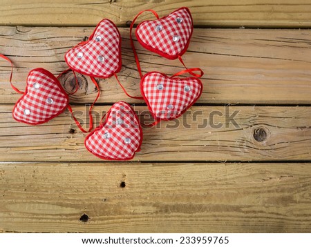 group of five red check hearts  with red ribbon on rustic wooden background
