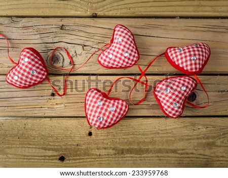five red check hearts  with red ribbon on rustic wooden background