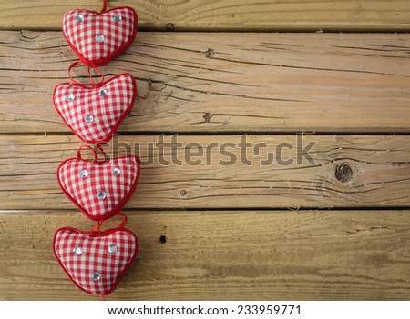 line of of four red check hearts  with red ribbon on rustic wooden background