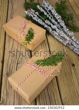 parcels wrapped in  brown paper with red and white string against an aged wooden background with conifer and glitter decoration