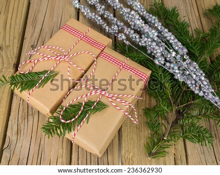 parcels wrapped in  brown paper with red and white string against an aged wooden background with conifer and glitter decoration