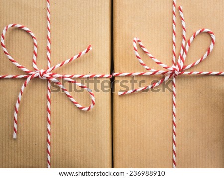detail of  two string and brown paper parcels : red and white striped  string bows against brown wrapping paper