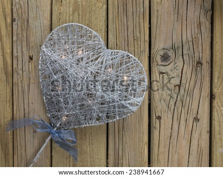 silver decorative christmas heart with led lights against a background of rustic wooden boards