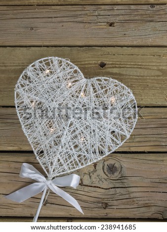 decorative white christmas heart with led lights against a background of rustic wooden boards