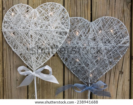 silver and white decorative christmas heart with led lights against a background of rustic wooden boards