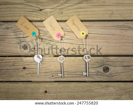 life choices concept: old keys hanging on rusty nails against wooden background with labels love, health, happiness,