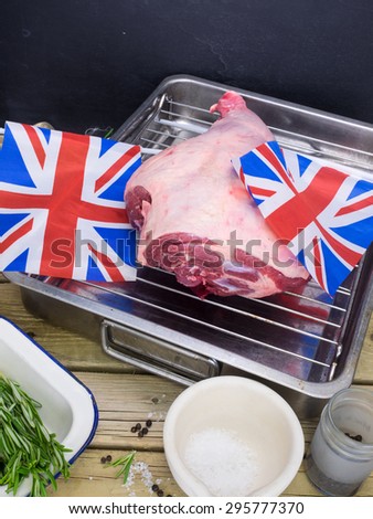 raw leg of lamb on roasting tin with salt pepper and fresh rosemary and british flags