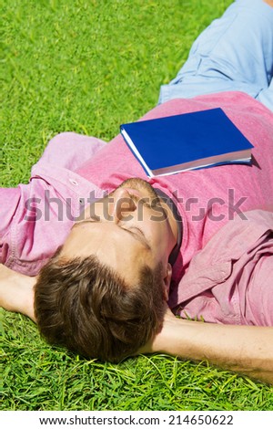 Happy man relaxing outdoors lying on the grass