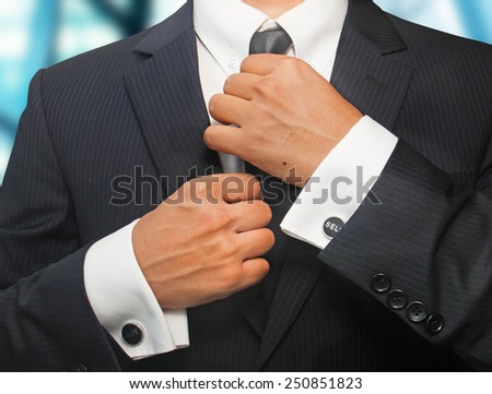 A man in a black suit straightens his tie
