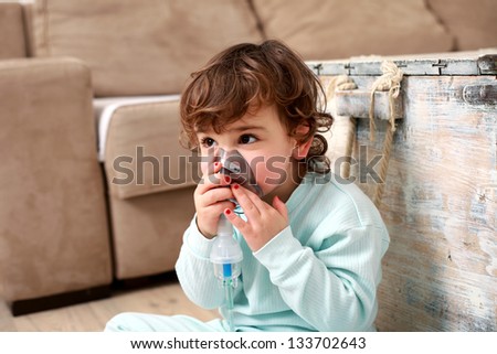Portrait of a cute little girl with inhaling mask at home