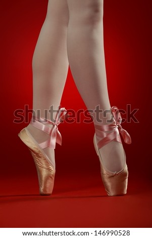 ballerinas crossed legs with ballet shoes on red background with satin cord