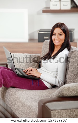 Young Woman Lounging in Living Room holding lap top