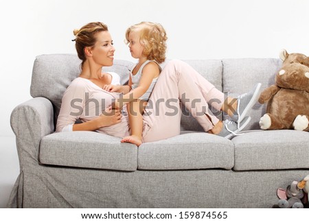 Mother and baby daughter playing on bad sofa 4