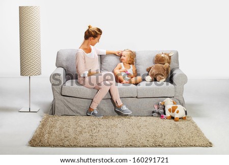 Mother and baby daughter playing on bad sofa 8