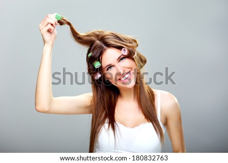 beautiful and cheerful girl with brown hair, hair dressing her  hair with green rollers